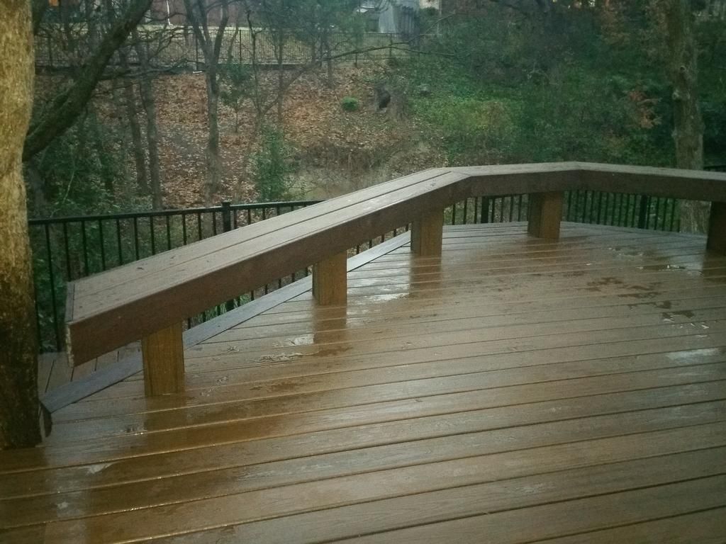 A wooden deck with a railing and a bench