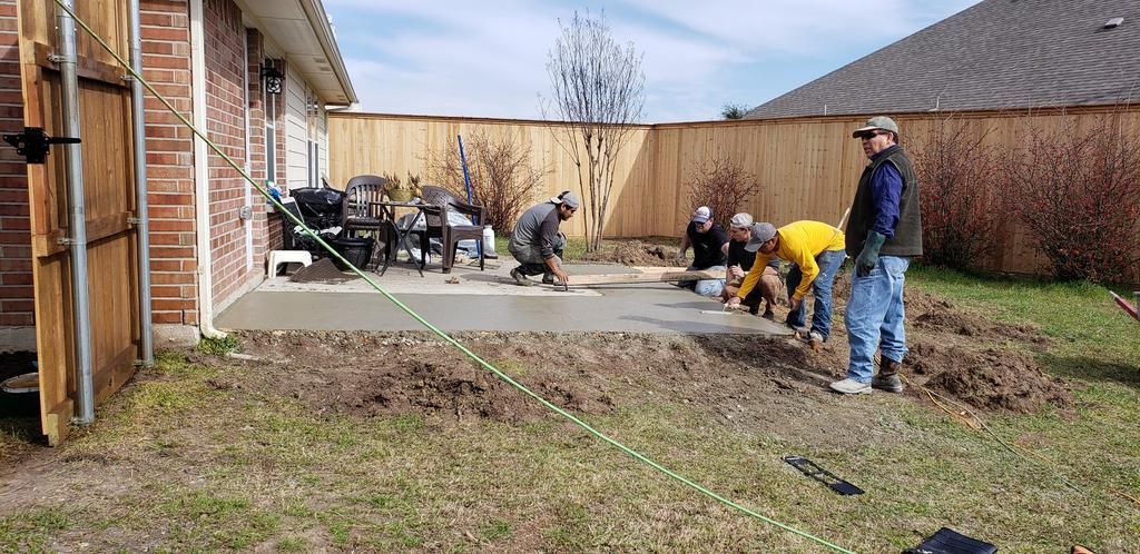 a group of people are working on a patio in a backyard