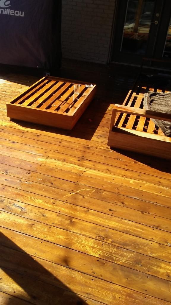 Two wooden chairs are sitting on a wooden deck.