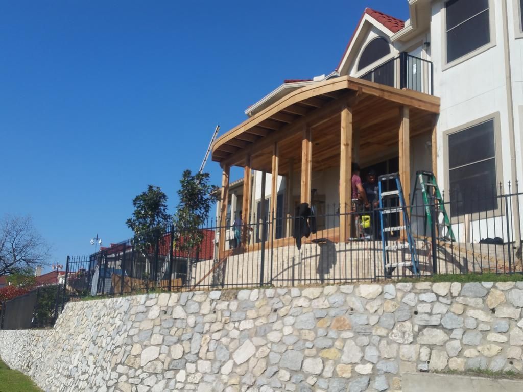 A large house with a stone wall and a wooden porch