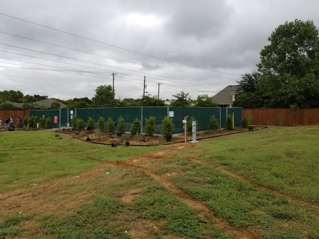 A green fence surrounds a lush green field