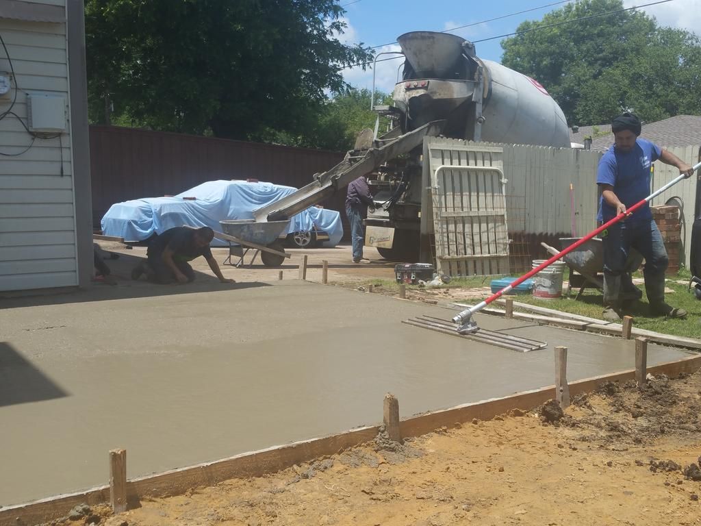 A man is raking concrete in front of a cement truck