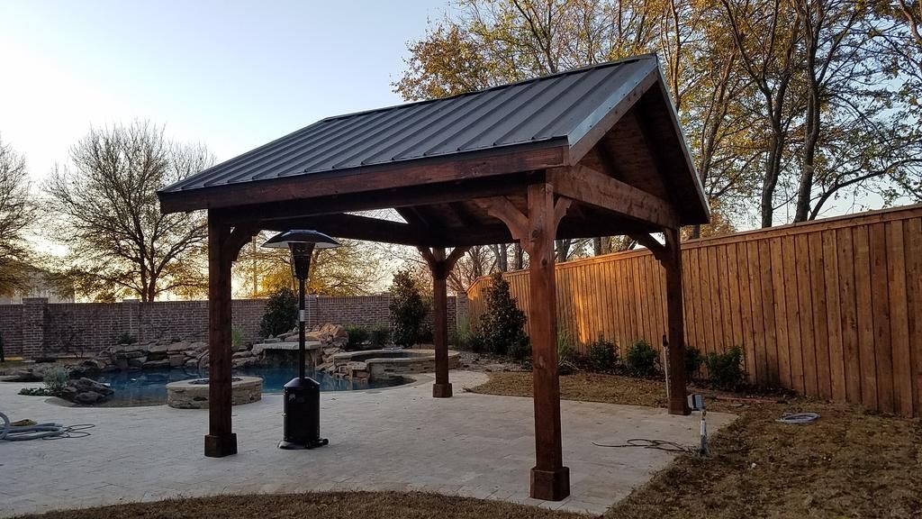 A wooden gazebo with a metal roof in a backyard next to a pool.