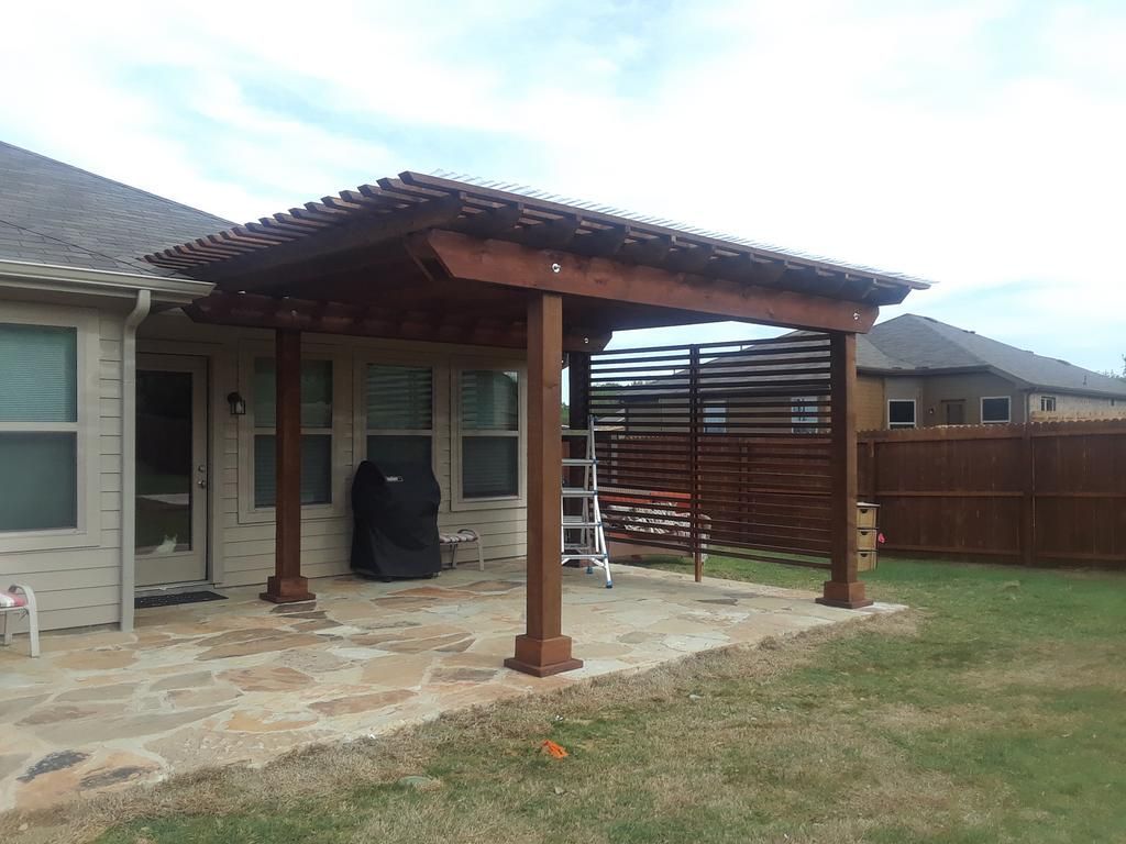 A wooden pergola is sitting in the backyard of a house.