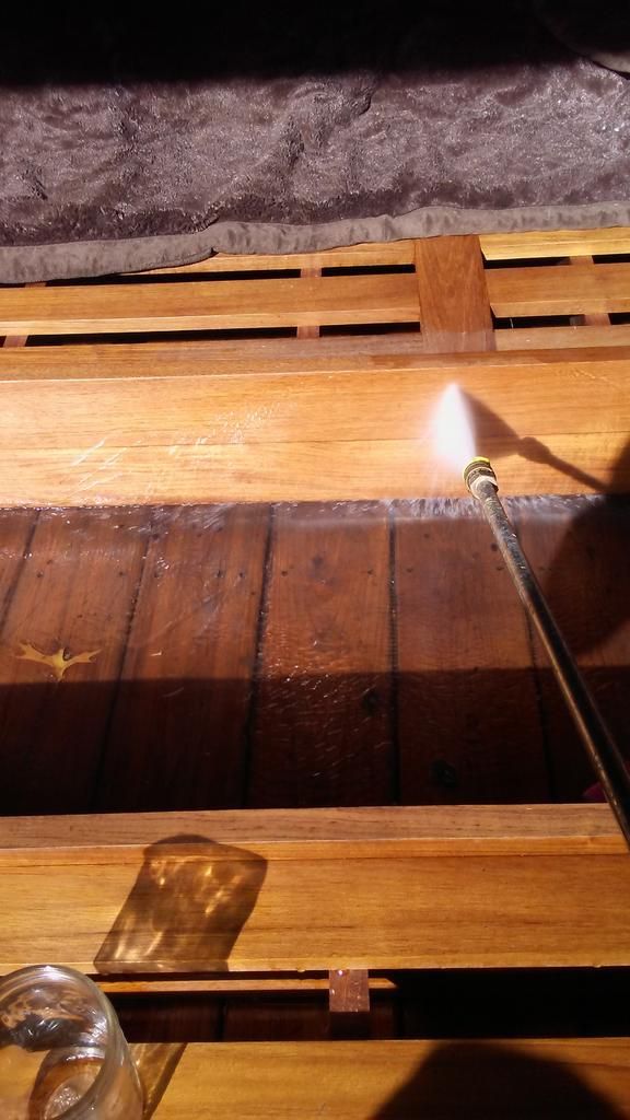 A person is using a torch to burn a piece of wood.