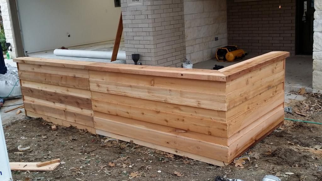 A large wooden box is sitting in the dirt in front of a brick building.