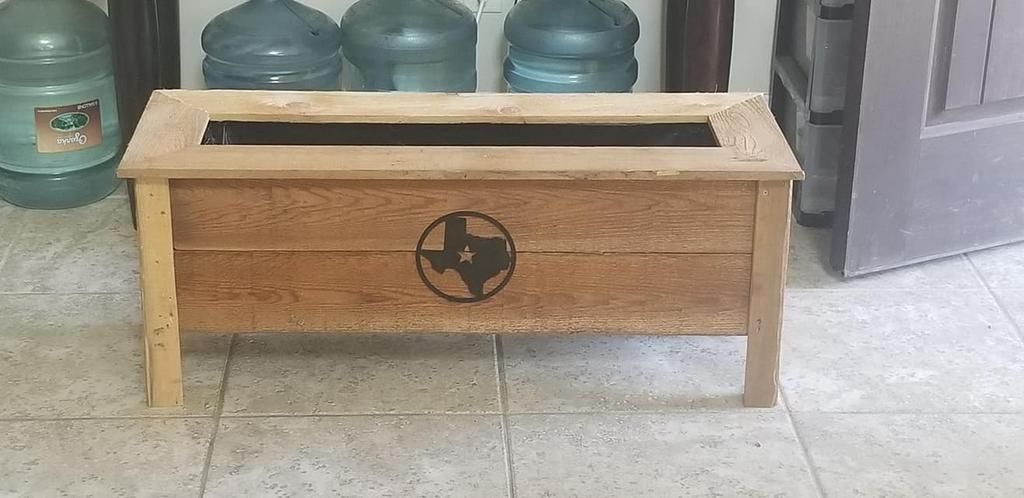 A wooden box with a texas flag on it is sitting on a tiled floor.