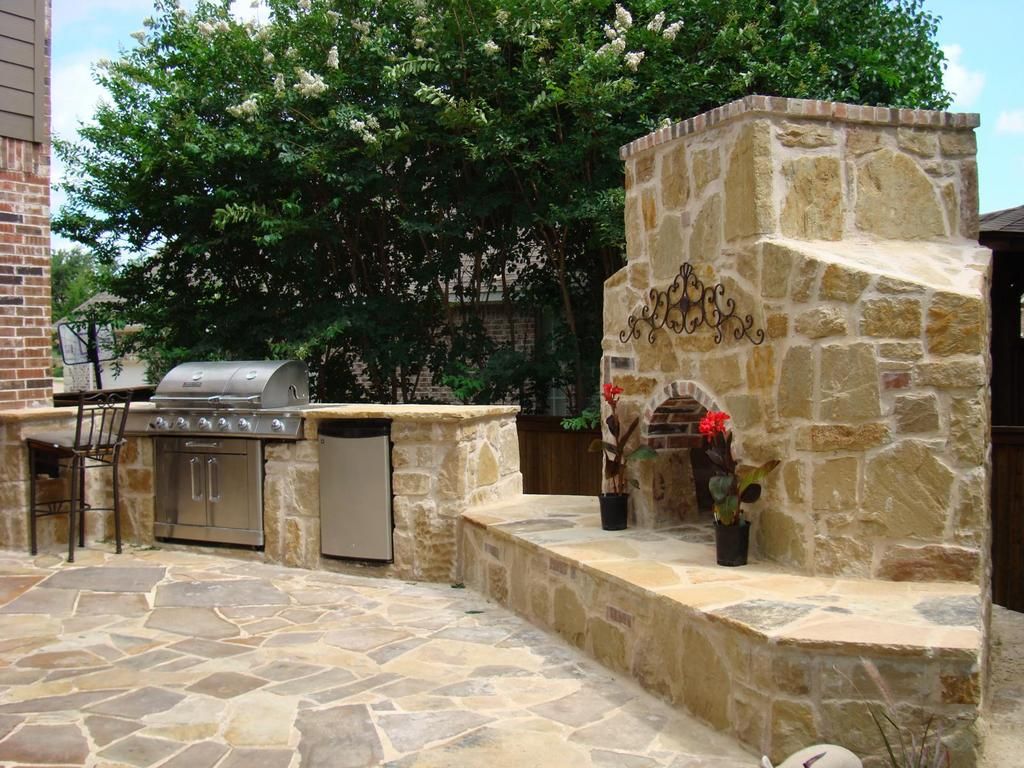 A patio with a grill and a stone fireplace