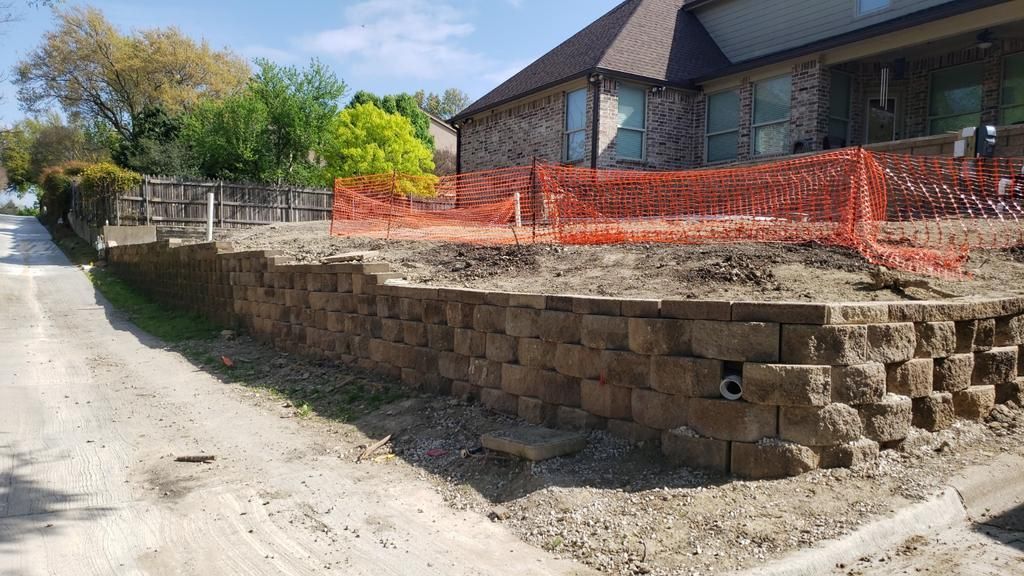 A stone wall is being built in front of a house.