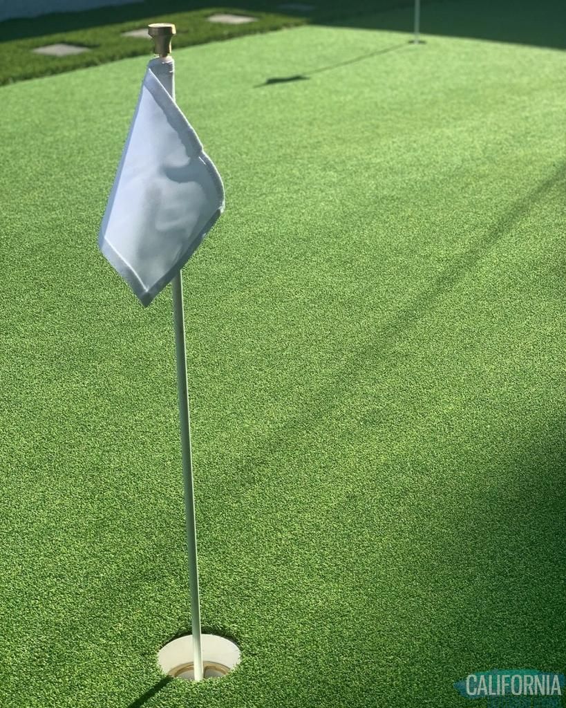 A white flag is sitting on top of a green golf course.