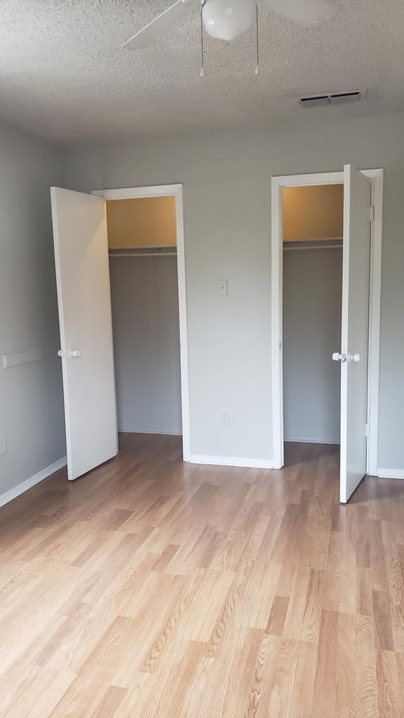 An empty bedroom with hardwood floors and two closets.
