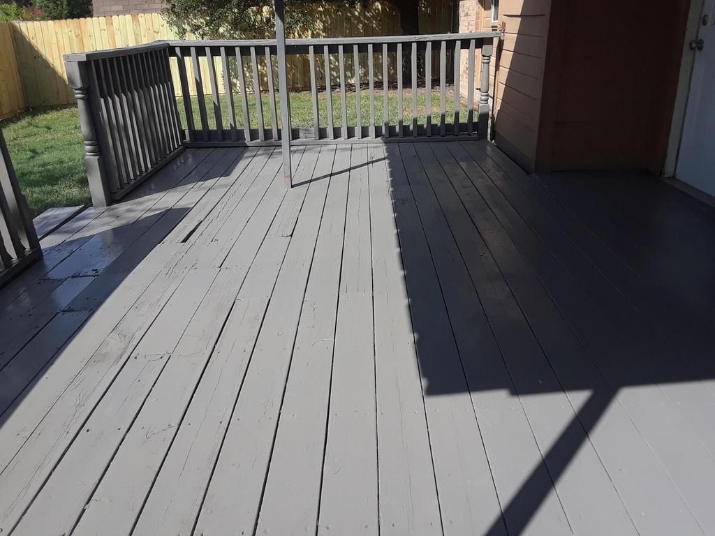 a gray deck with a railing and a shadow on it