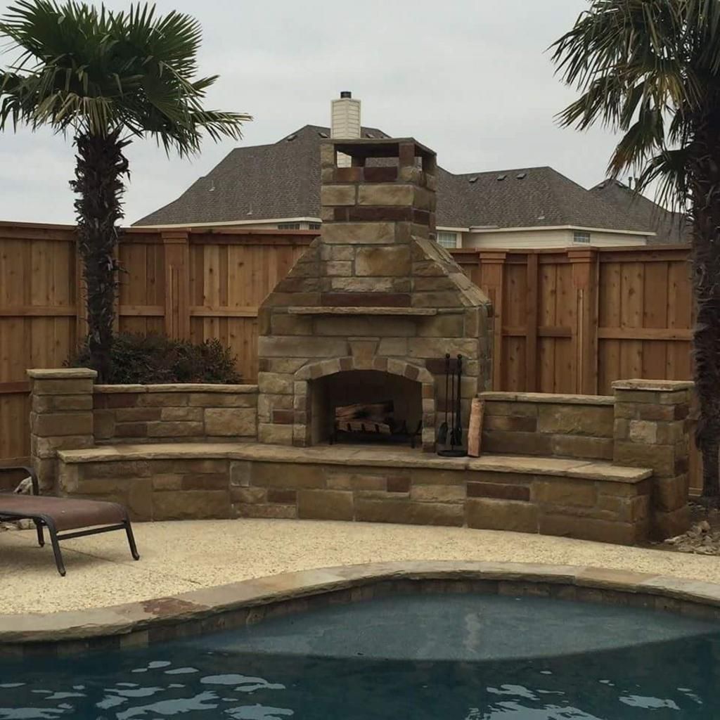 A stone fireplace sits next to a swimming pool