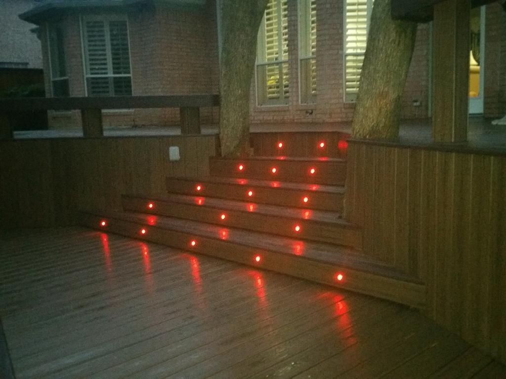 A wooden deck with red lights on the stairs