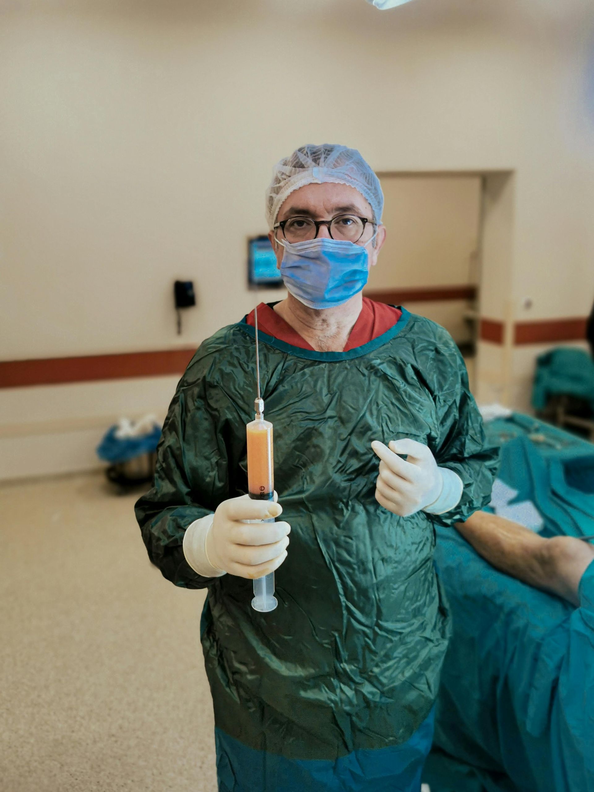 A surgeon holding a syringe in an operating room