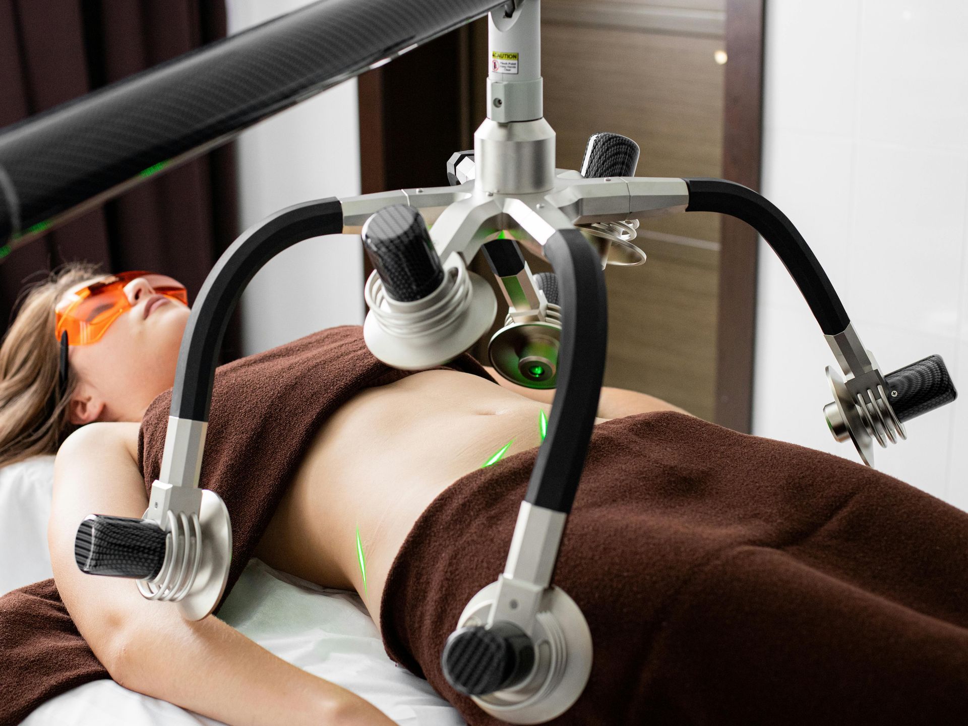 A woman laying on a bed getting a laser treatment on her stomach.