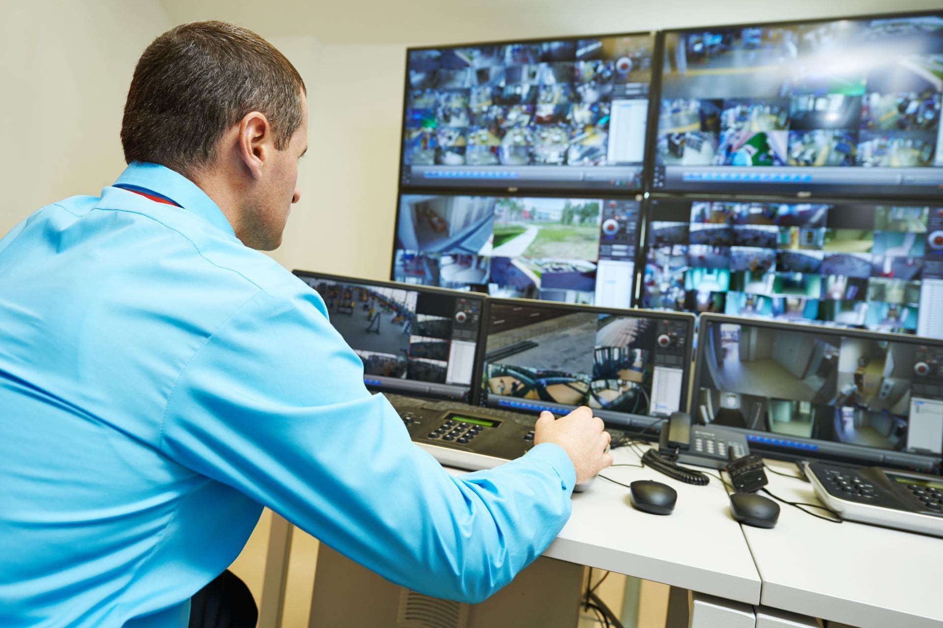 A man is sitting at a desk in front of a bunch of monitors.