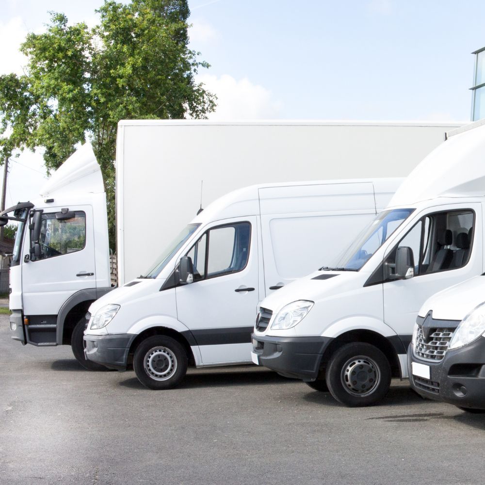 Three white vans are parked next to each other in a parking lot