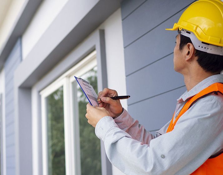 a man wearing a hard hat is writing on a clipboard .