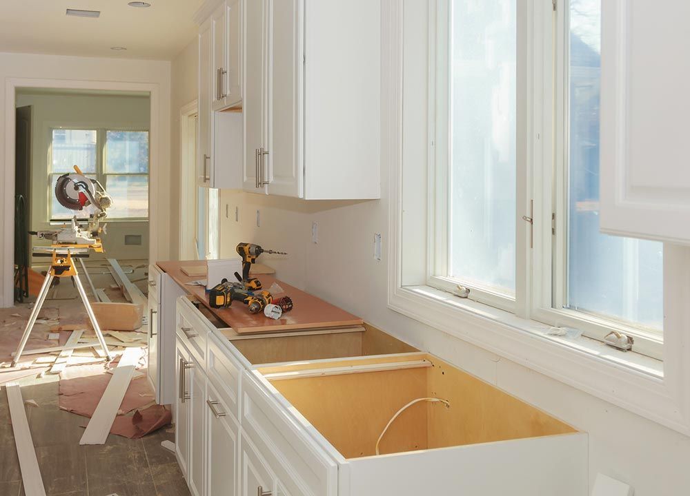 a kitchen under construction with white cabinets and a sink .