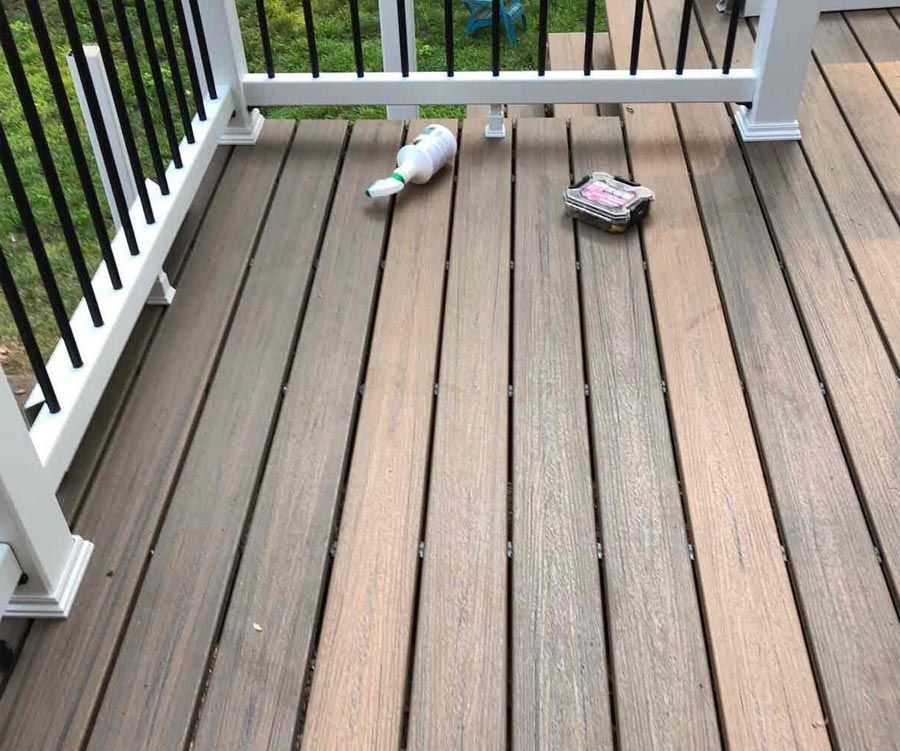 a wooden deck with a white railing and a bottle on it .