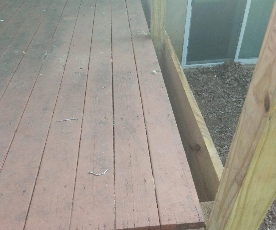 a wooden deck with a sliding glass door in the background