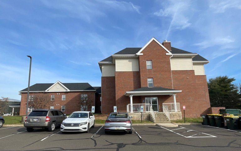 a large brick building with a brand new roof with cars parked in front of it .