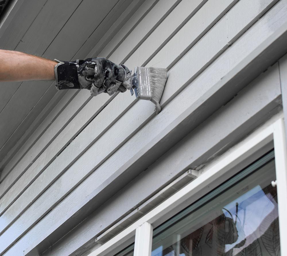 a person is painting the side of a house with a brush .