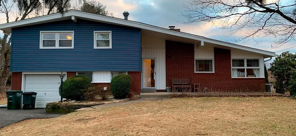 a red brick house with a blue siding and a white garage door .