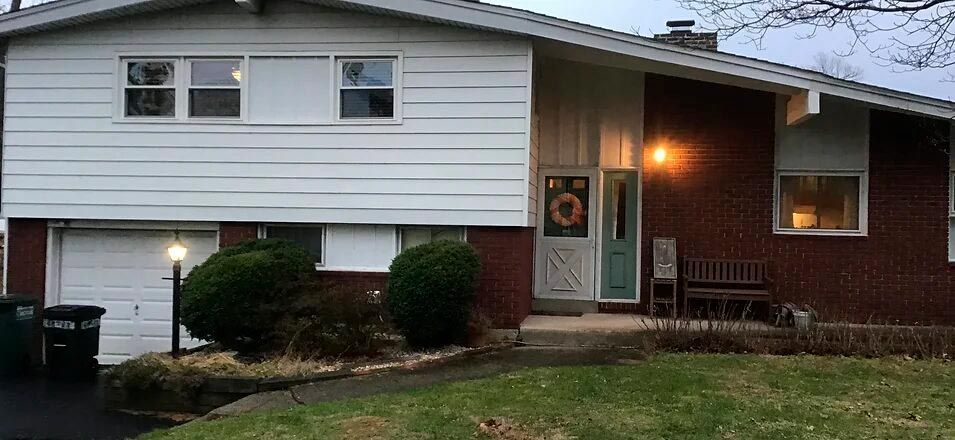 a brick house with a white siding and a green door .