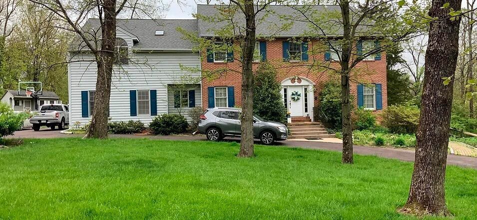 a large house with a car parked in front of it surrounded by trees .