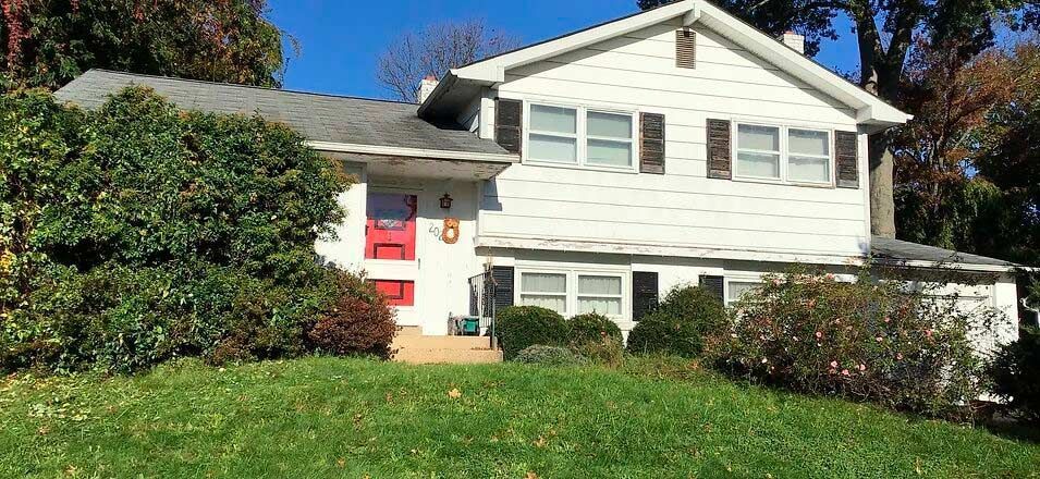 a white house with red doors is sitting on top of a lush green hillside .