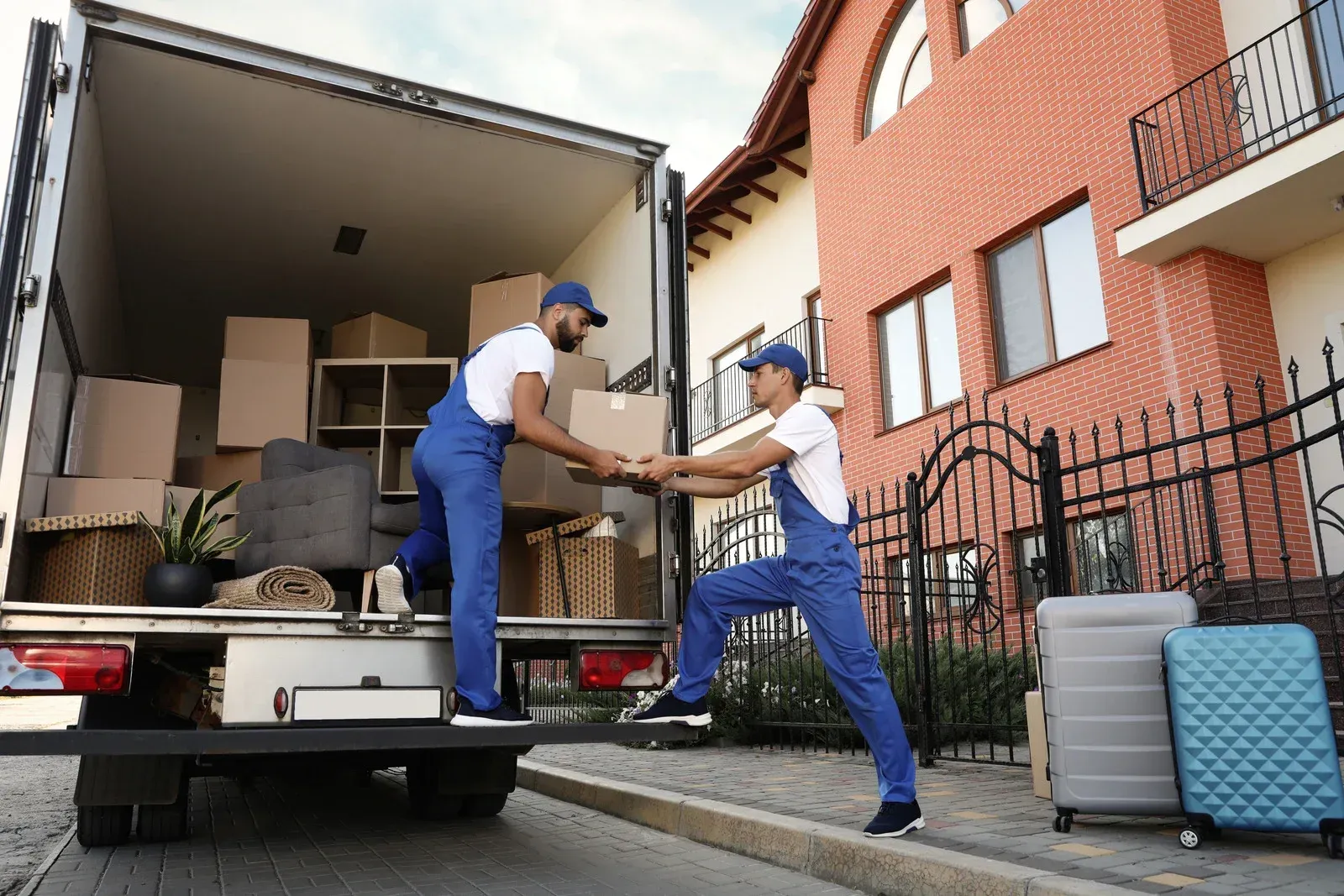 Two movers loading boxes onto a truck from a building.