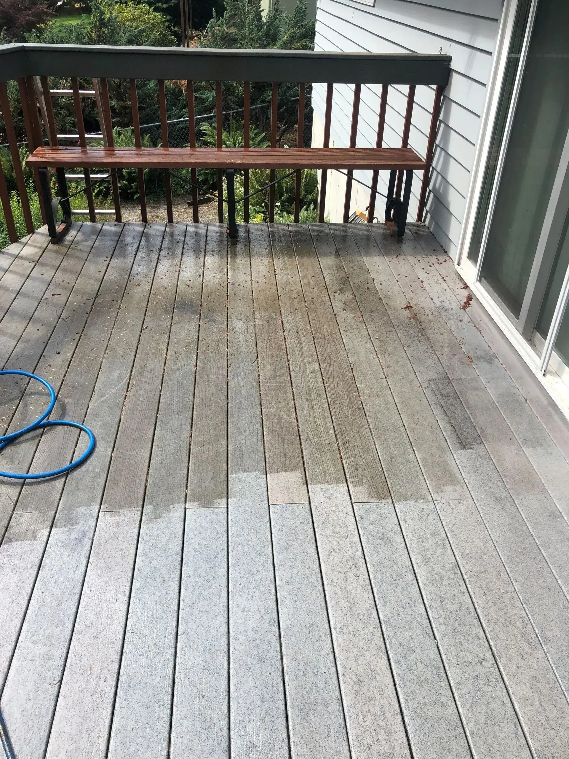 A wooden deck is being cleaned with a hose.