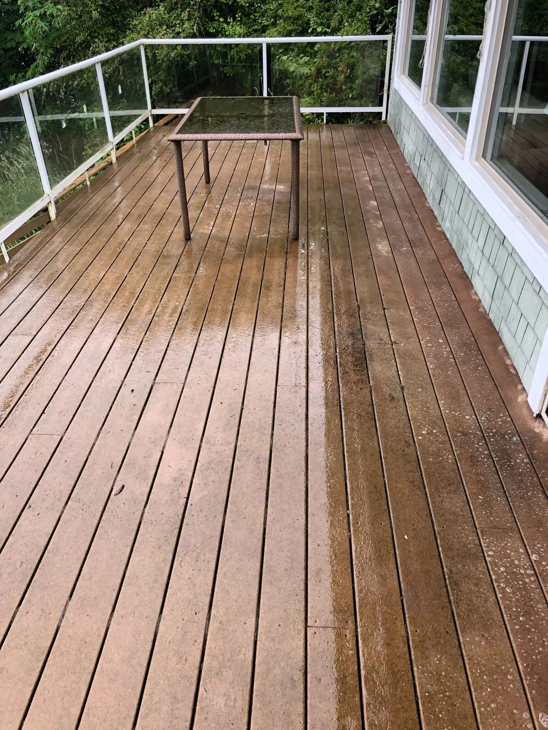 A wooden deck with a table on it and a window.