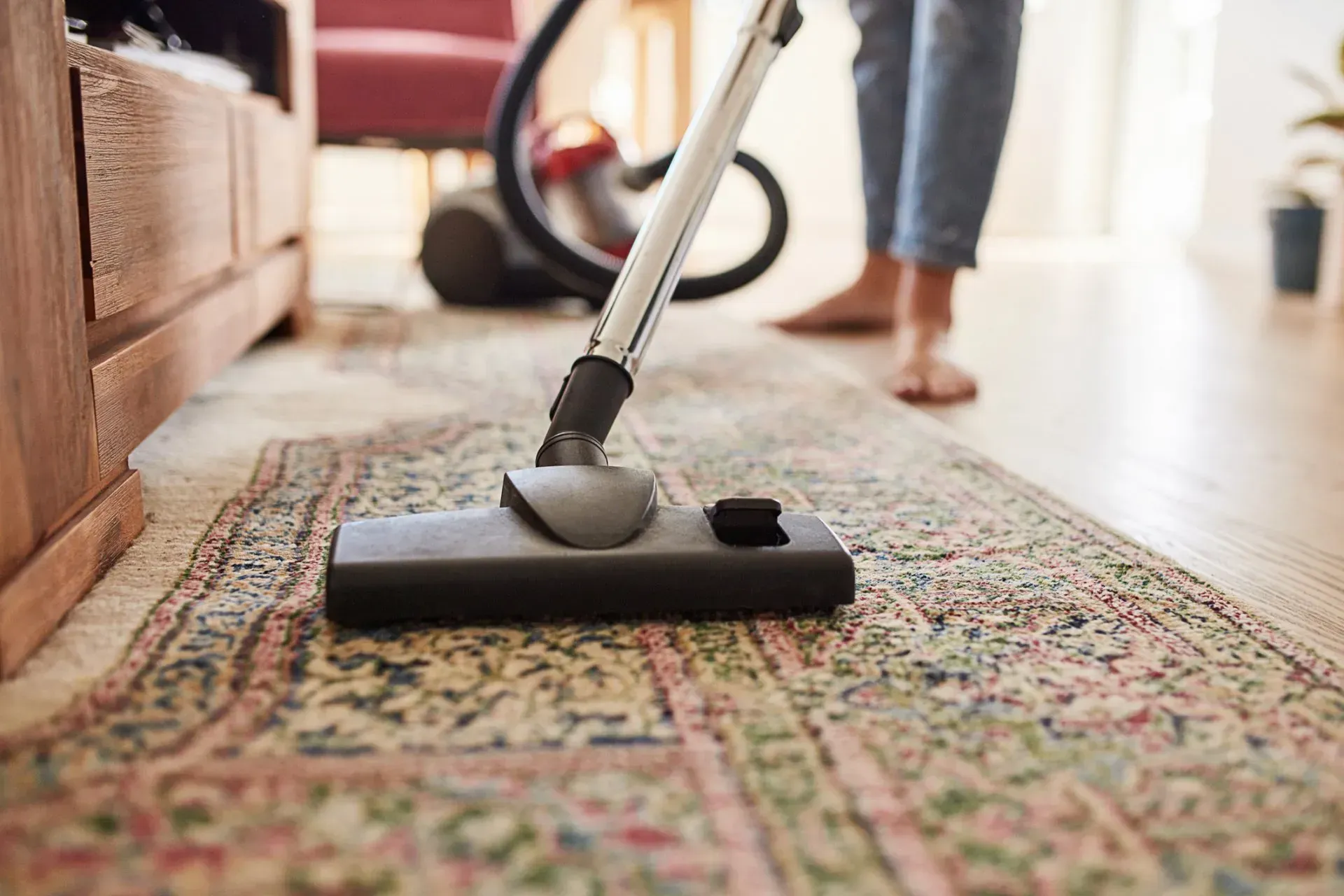 A person is vacuuming a rug in a living room.