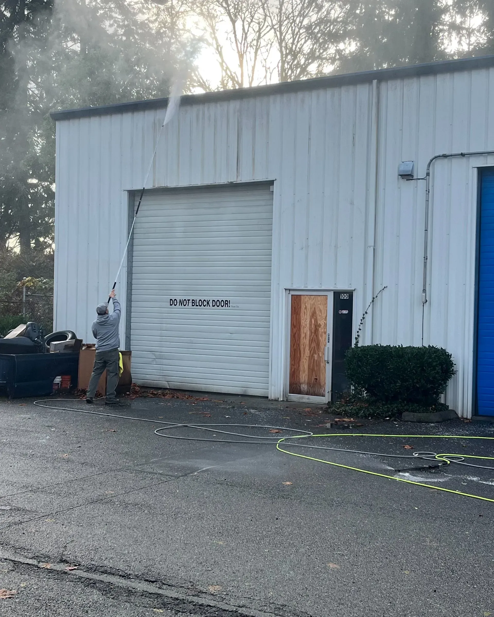 A man is spraying a garage door with a hose.