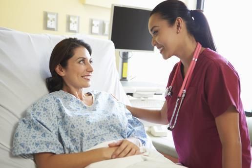 A nurse is talking to a patient in a hospital bed