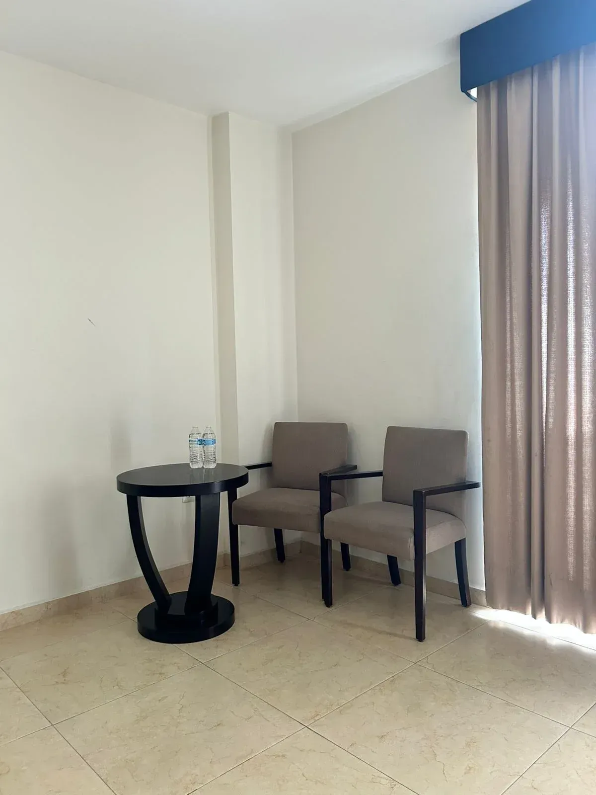 Dos sillas tapizadas en gris y una pequeña mesa auxiliar redonda.