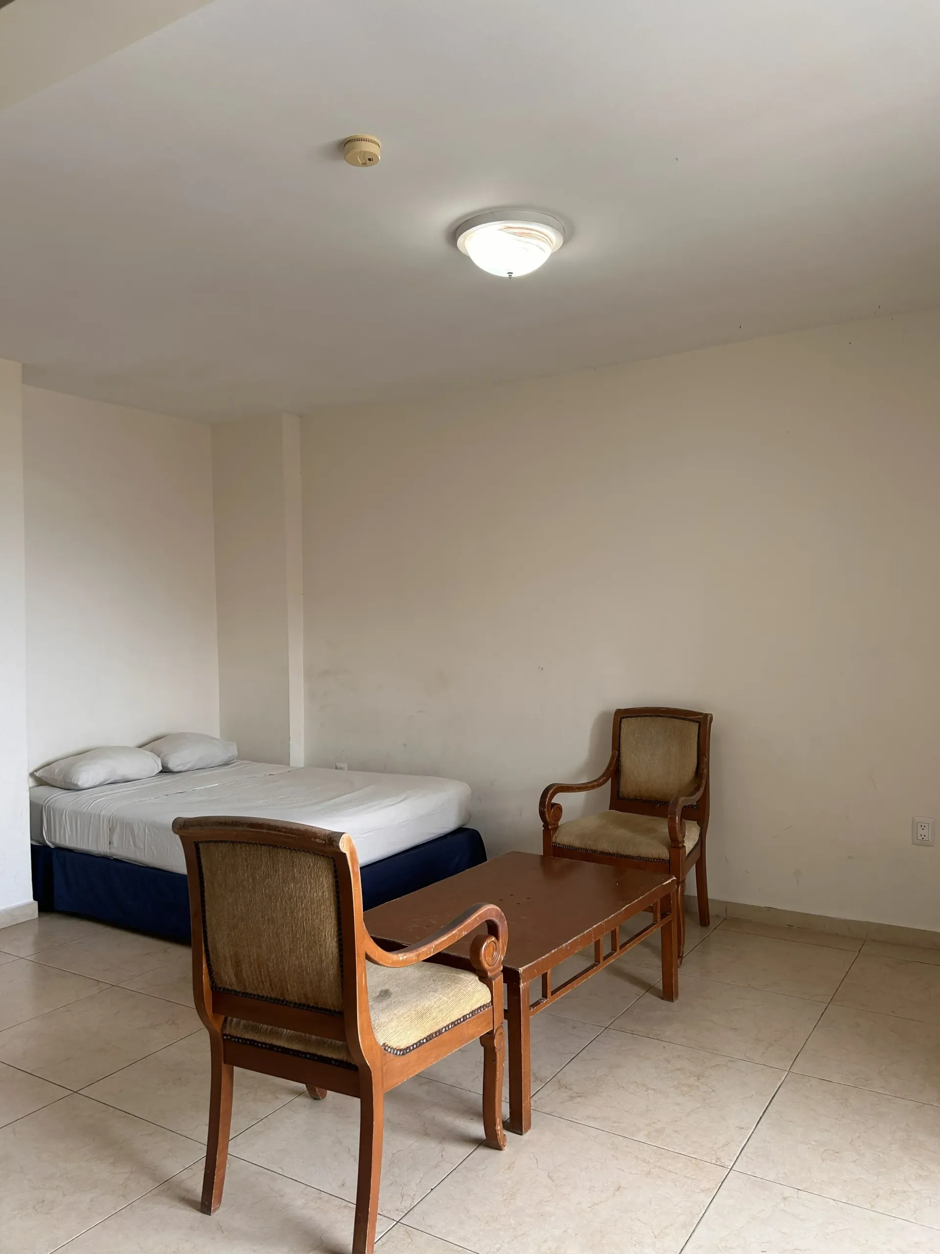 Una habitación con una cama con ropa de cama blanca, una mesa de centro de madera.