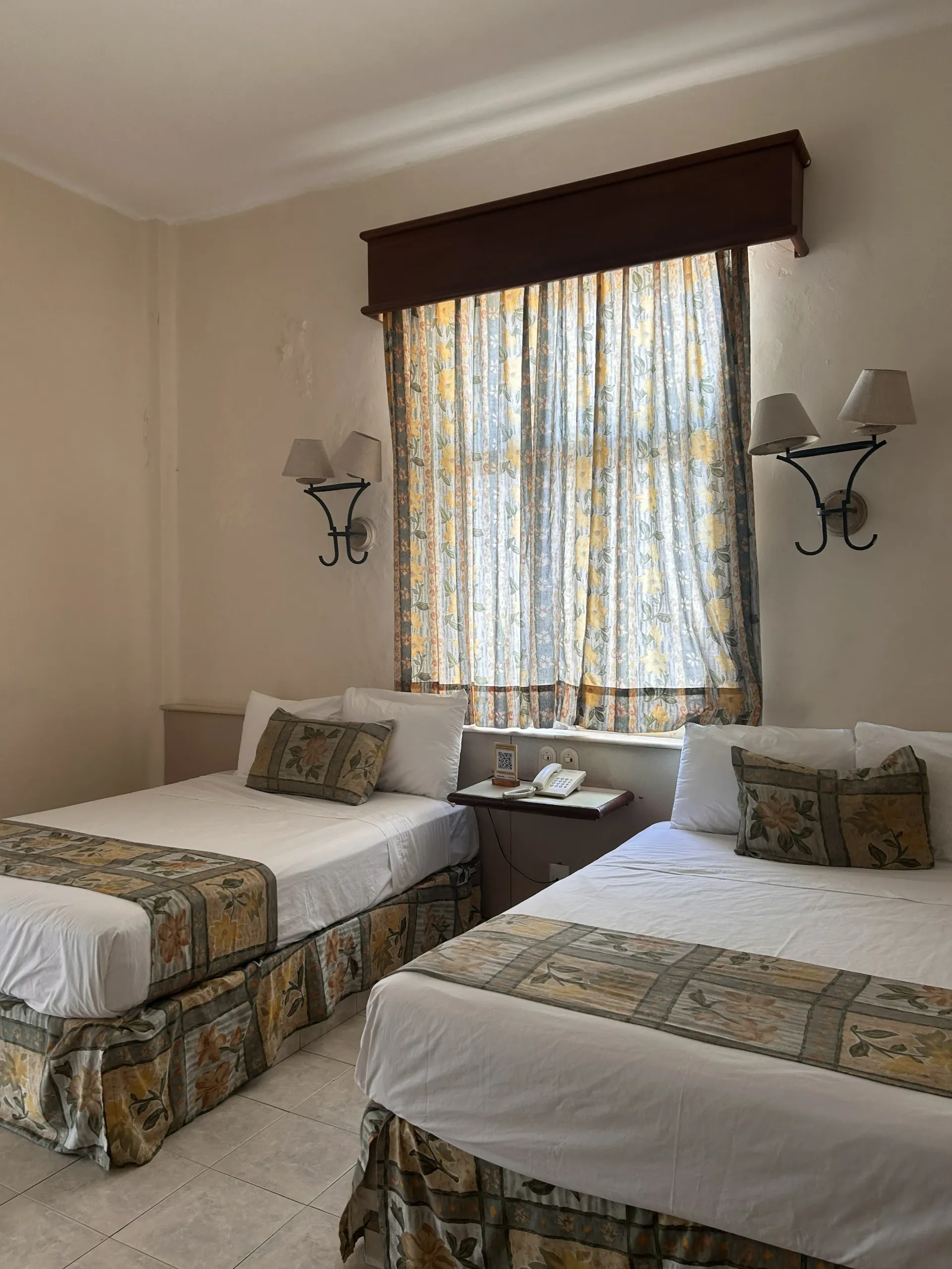 Una habitación de hotel con dos camas, colchas y almohadas a juego.