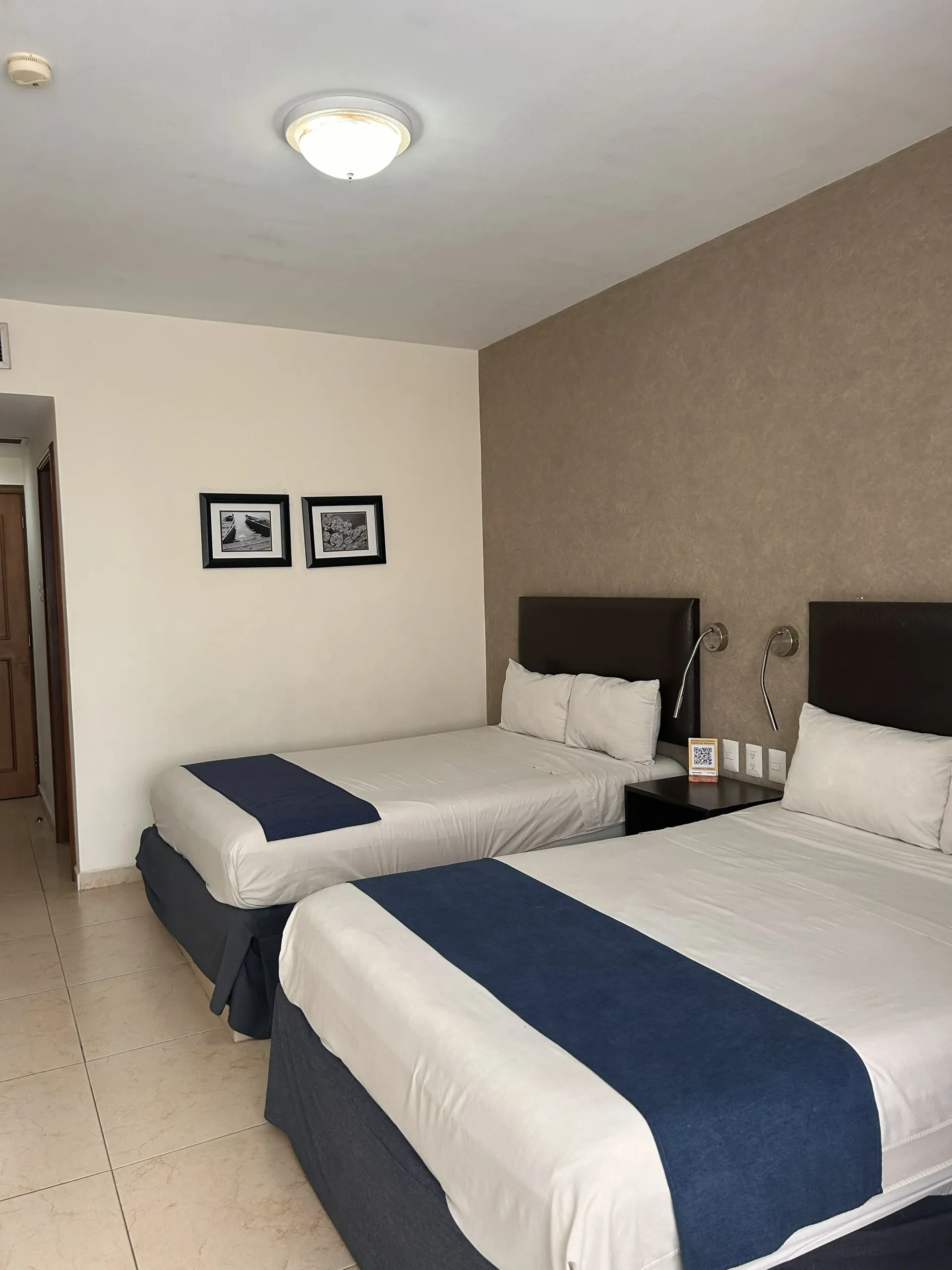 Una habitación de hotel con dos camas, con ropa de cama blanca.