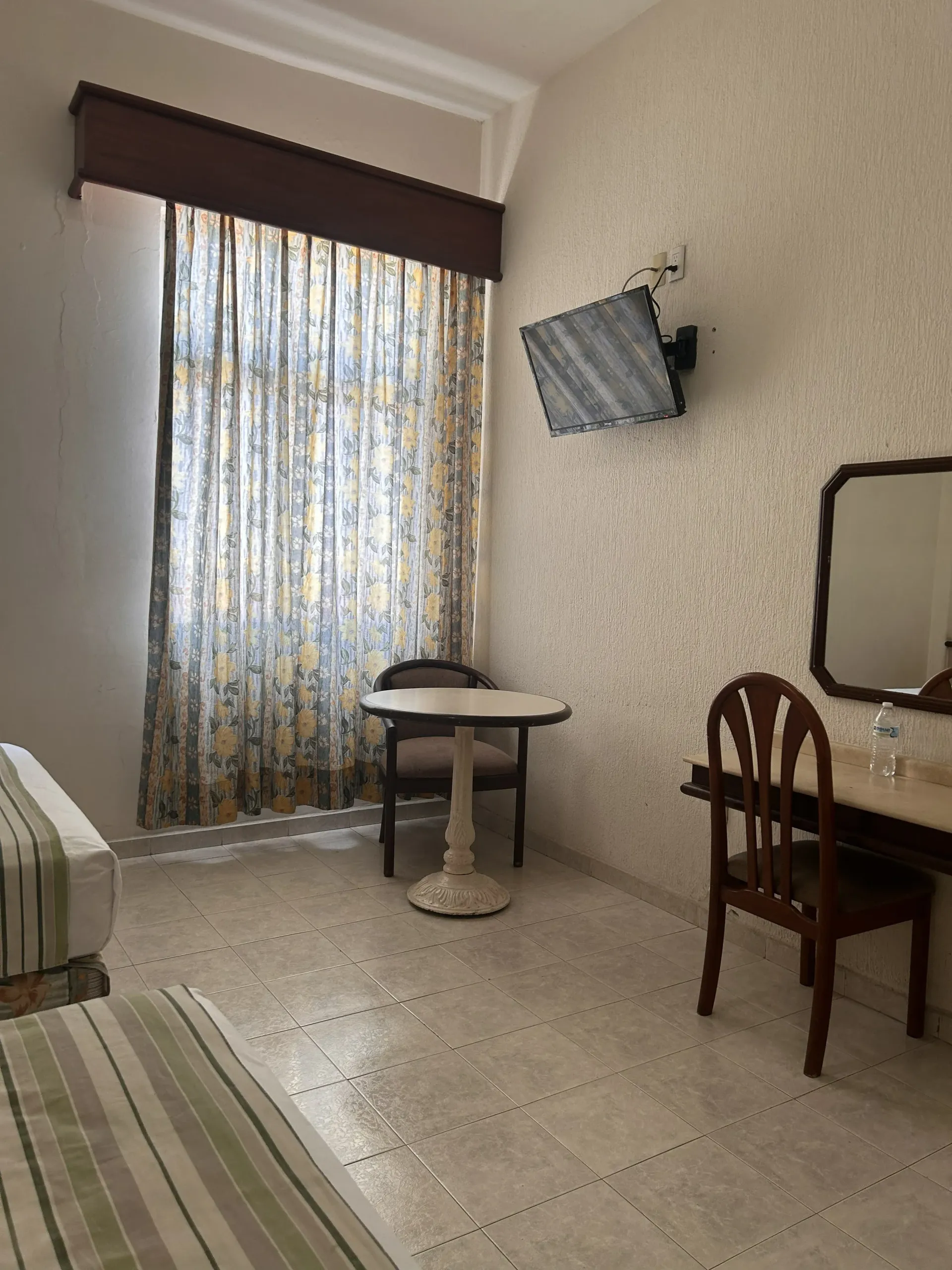 Una habitación de hotel con dos camas, una pequeña mesa redonda con una silla.