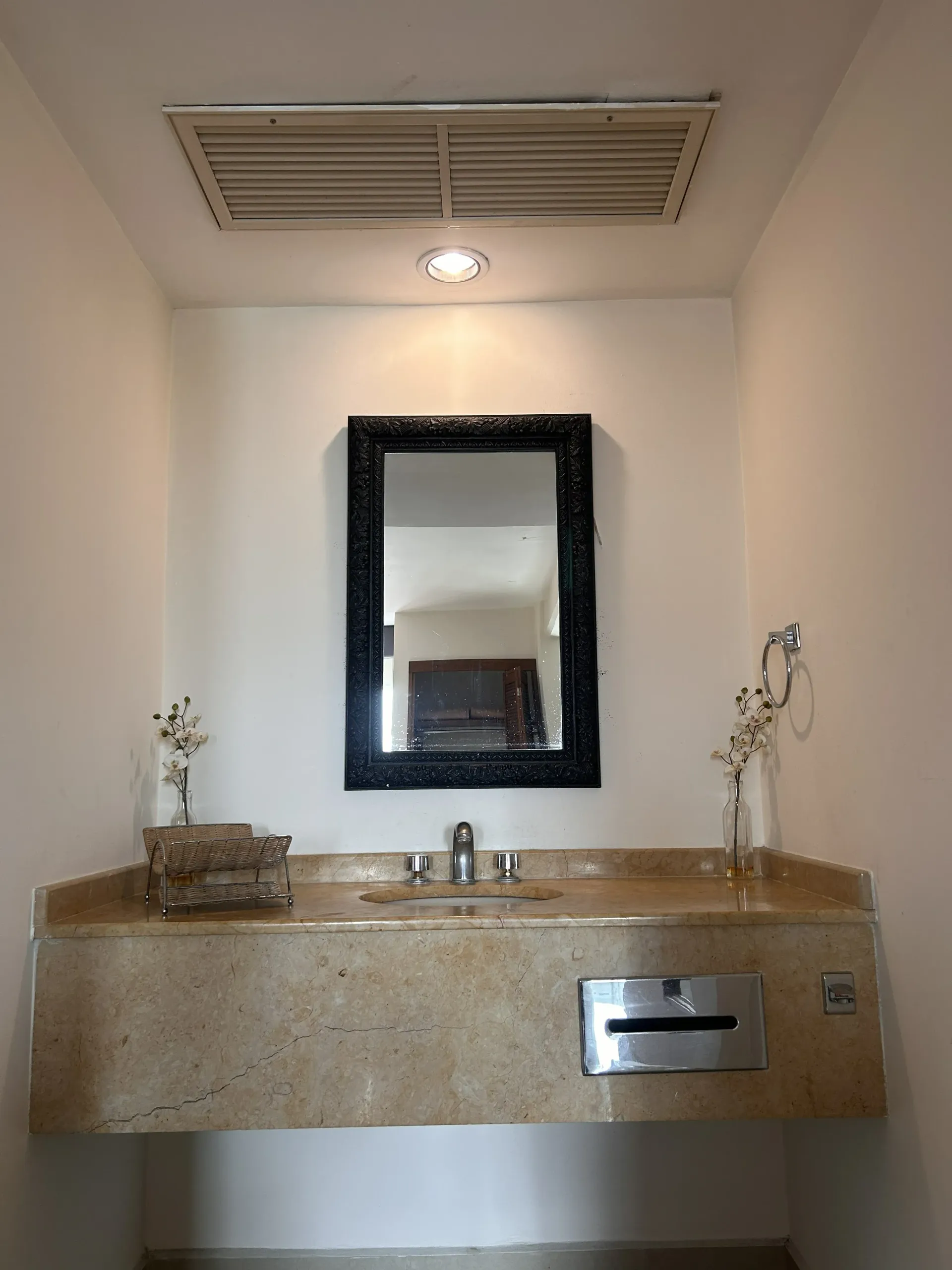 Un mueble de baño con encimera de piedra beige, lavabo central y espejo.