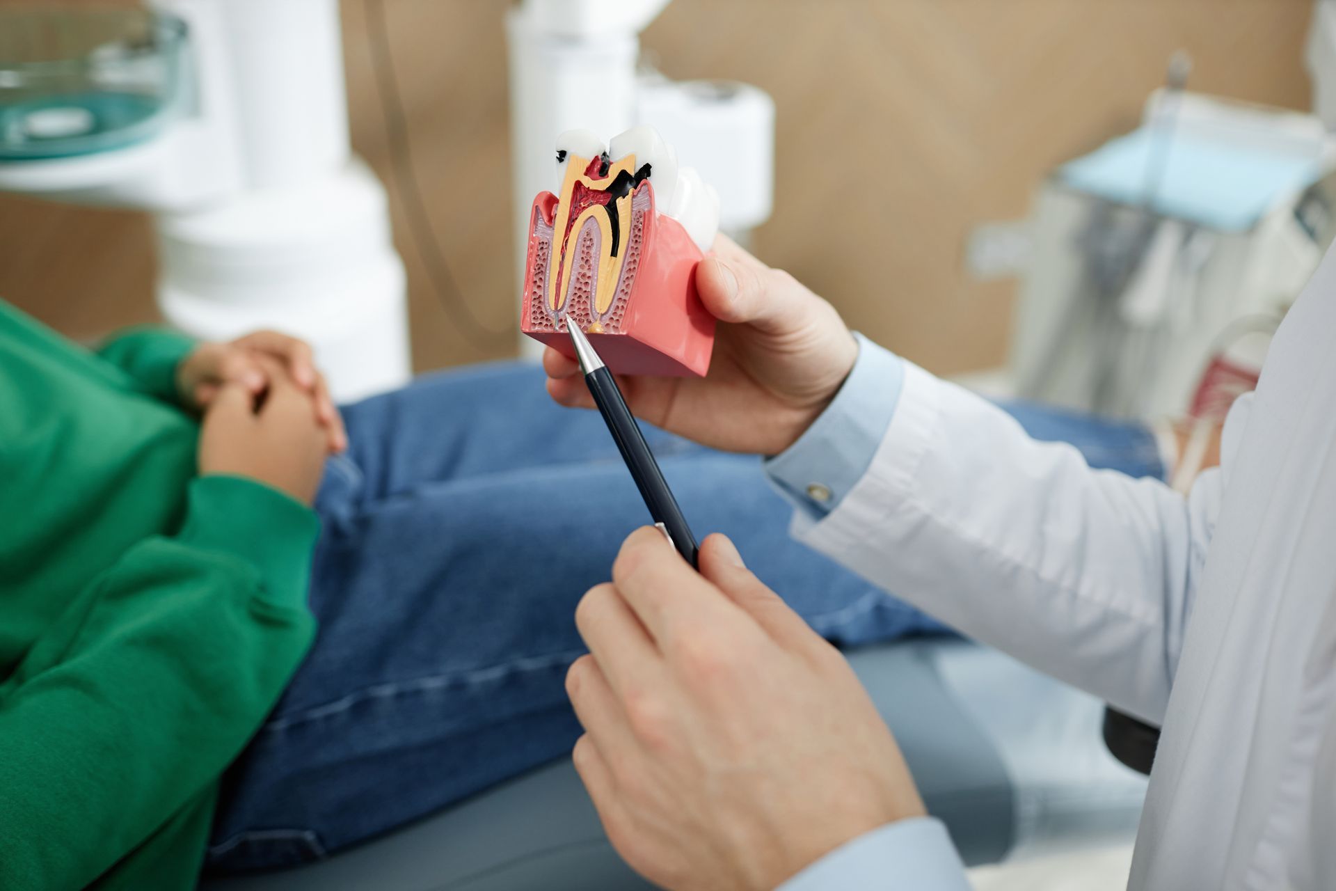 A man is sitting in a dental chair looking at his teeth in a mirror.