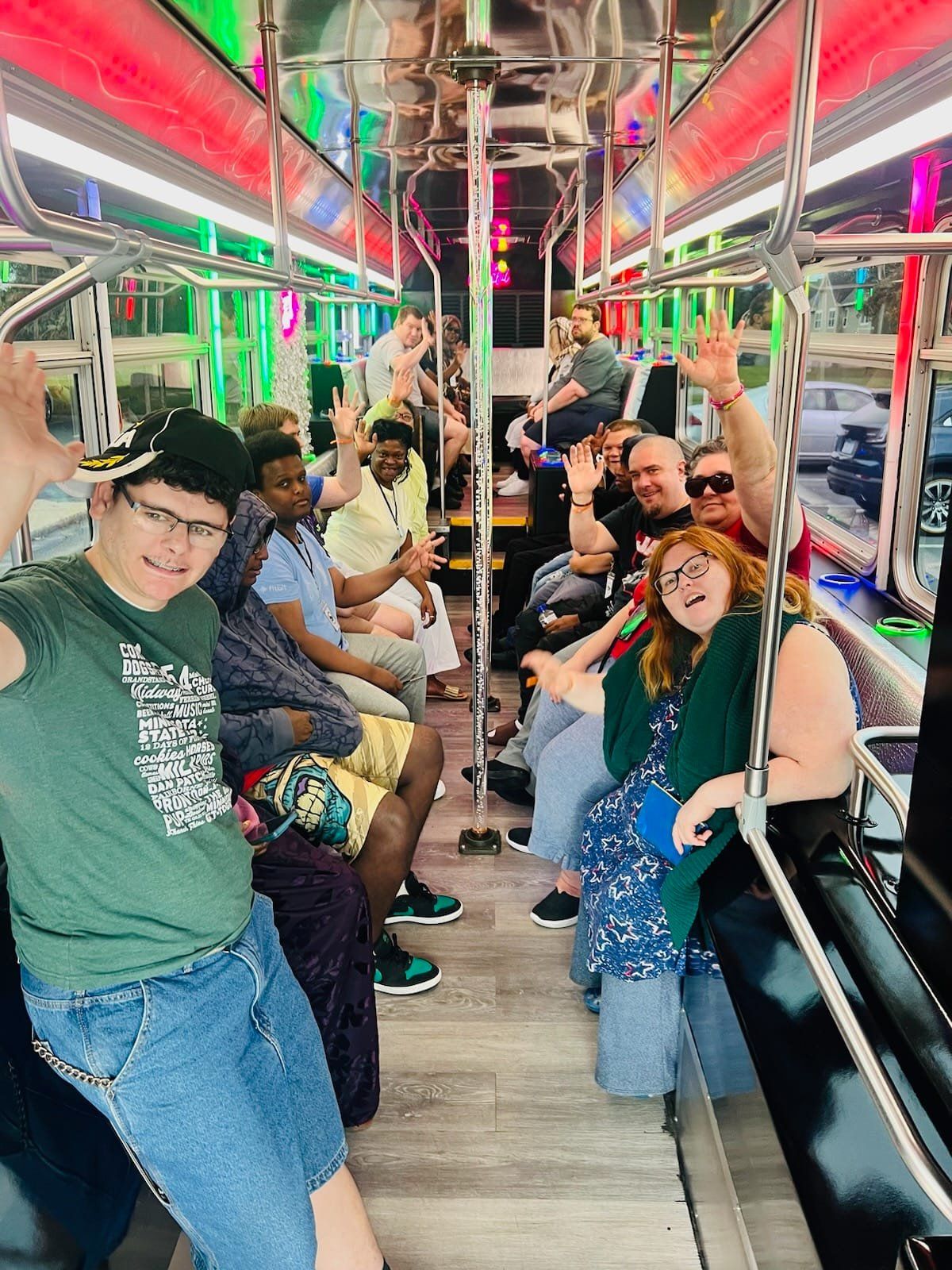 People waving from inside a party trolley decorated with colorful lights.