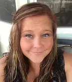 Woman with auburn hair and highlights, smiling, outdoors.