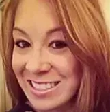 Woman with light brown hair, smiling with teeth visible.