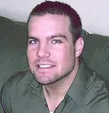 Man with short dark hair, wearing a green button-down shirt, smiling.