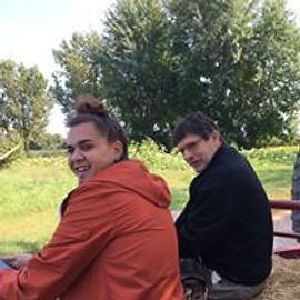 Two people on a hayride: one in an orange jacket, the other in a black sweater